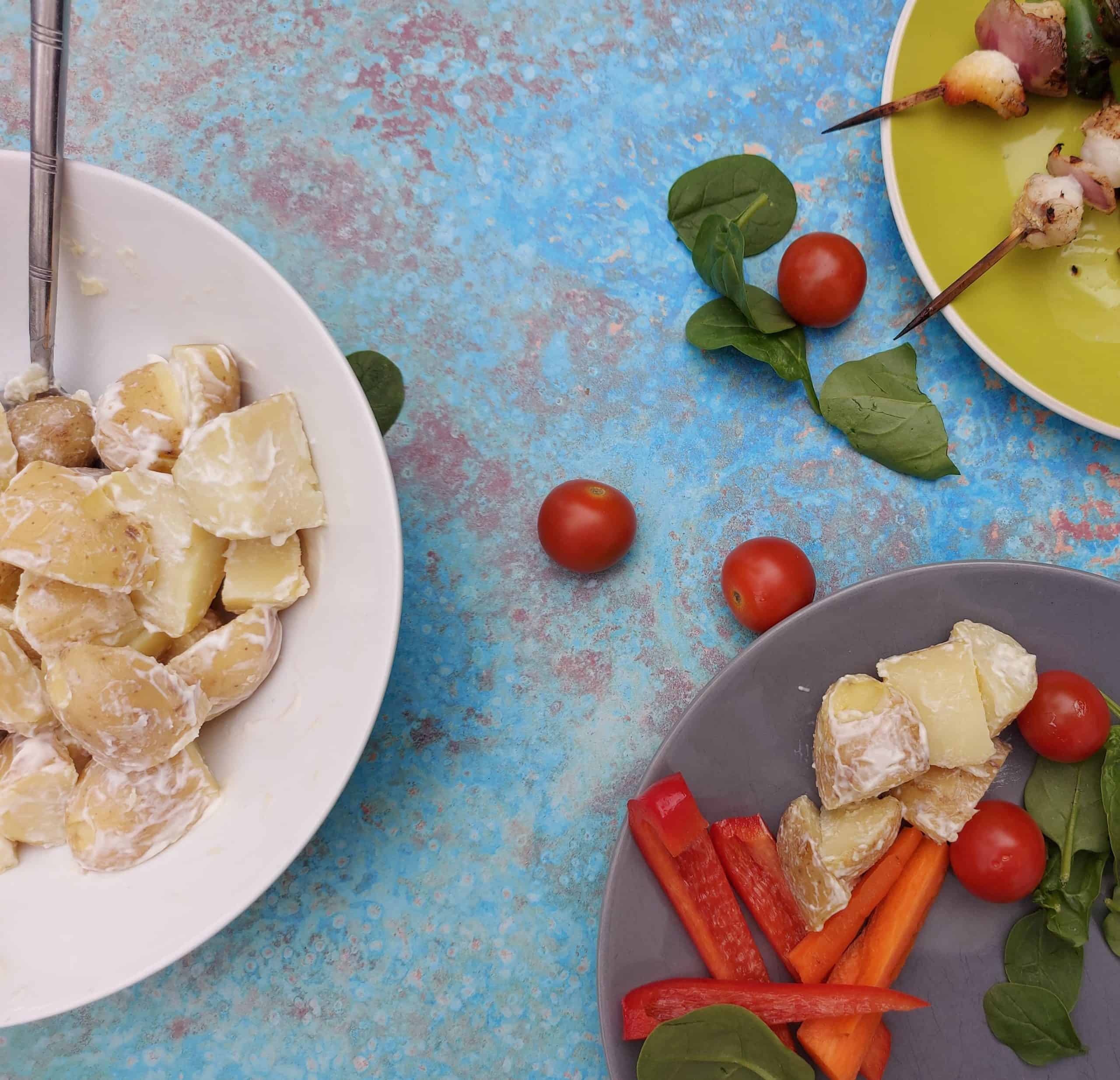 potato salad and chopped red peppers, BBQ skewers against a blue background