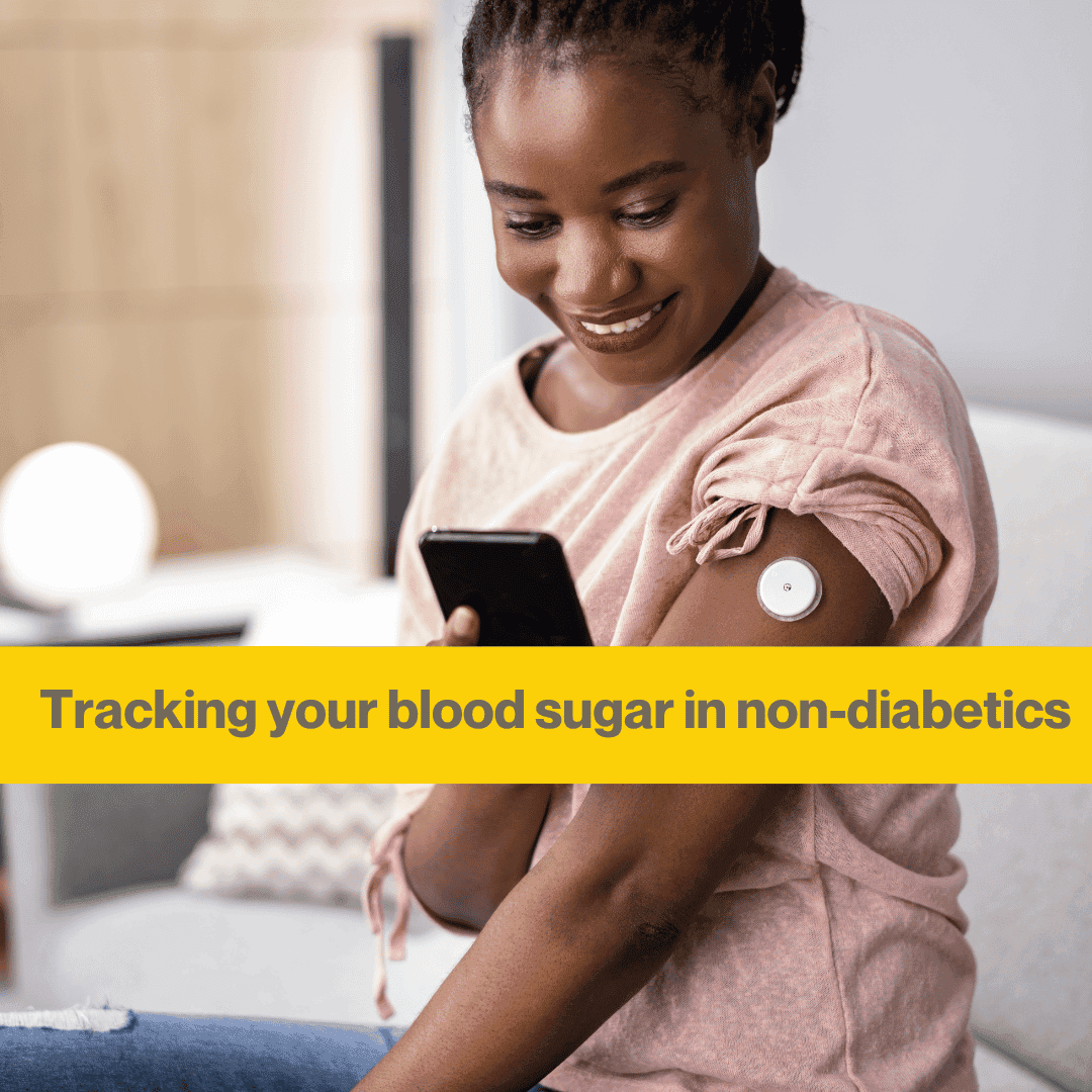 black woman sitting on a sofa looking at her phone. She has a white continuous glucose monitor in her arm and is smiling at her phone.