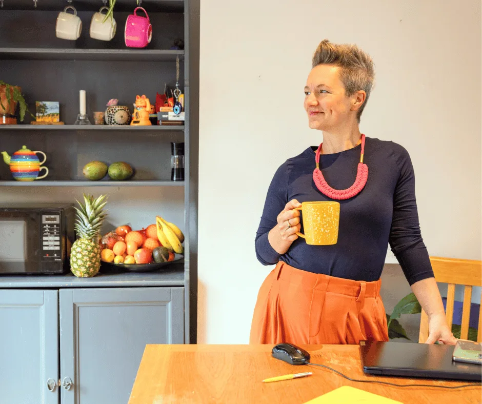 Nutritionist reviewing a meal plan with a man seated at a table, with fruits, a clipboard, and healthy food items visible in a bright kitchen setting.